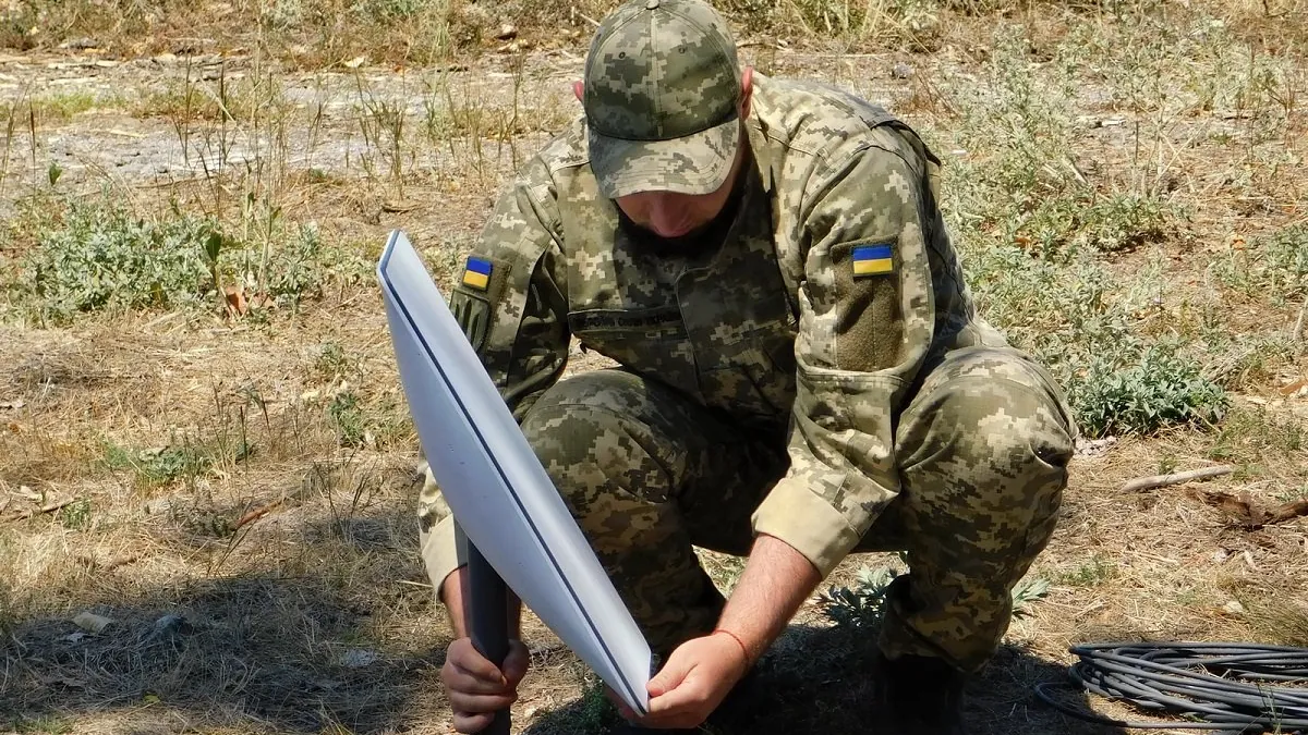 Symbolic image: Ukrainian soldier setting up a Starlink terminal