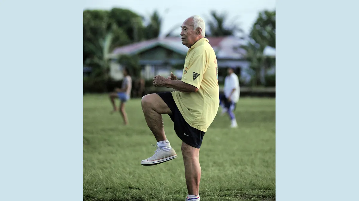 Symbolbild: Älterer Mann macht Gymnastikübungen auf einer Wiese