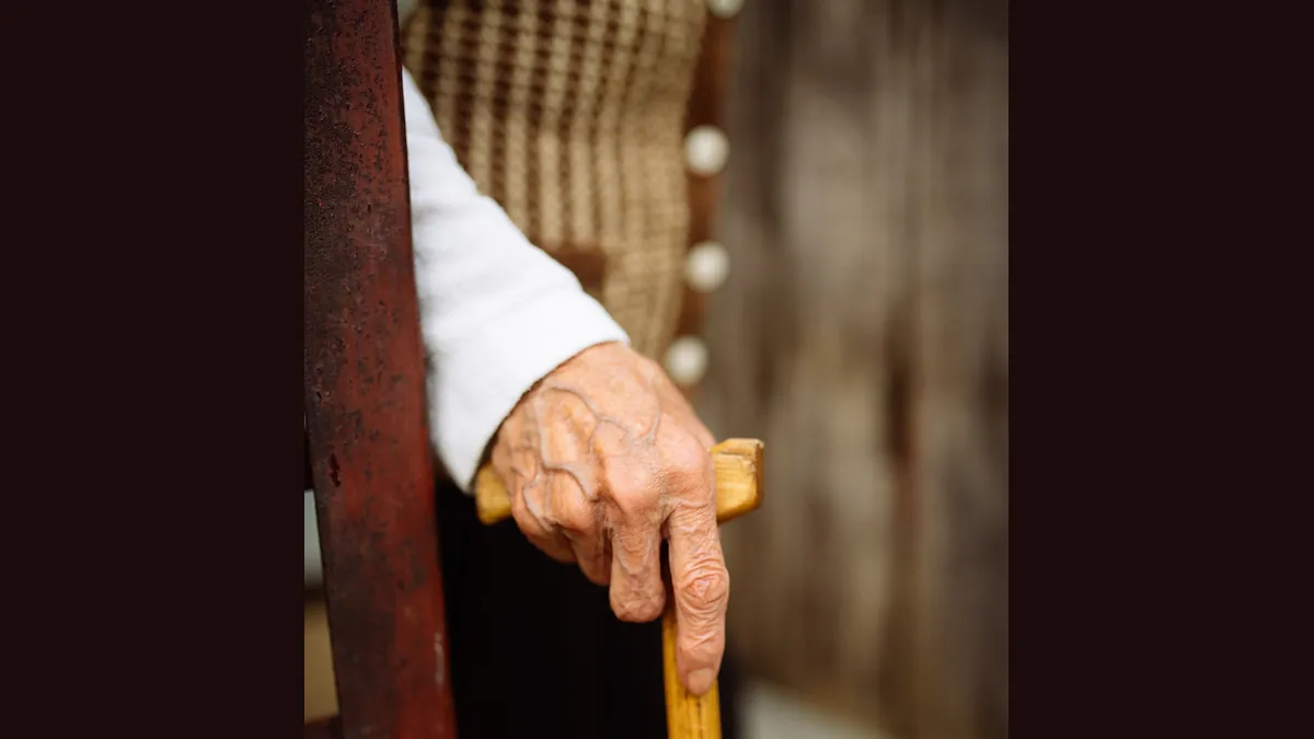 An older person's hand resting on a walking stick (symbolic image)